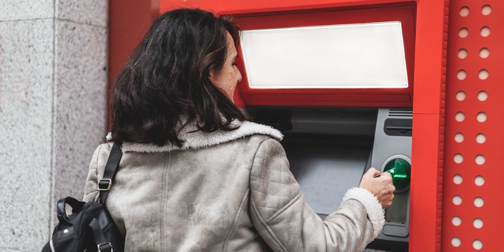 Frau an Bankautomaten zieht Geld ab