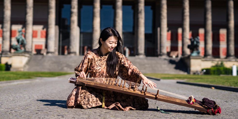 Musikerin Hyunjeong Park spielt Gayageum vor dem Alten Museum in Berlin