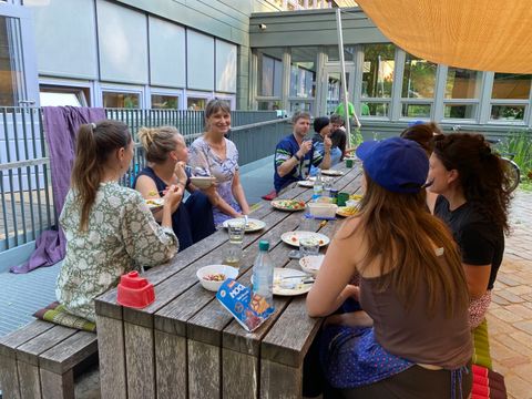 Menschen sitzen gemeinsam um Tisch und essen