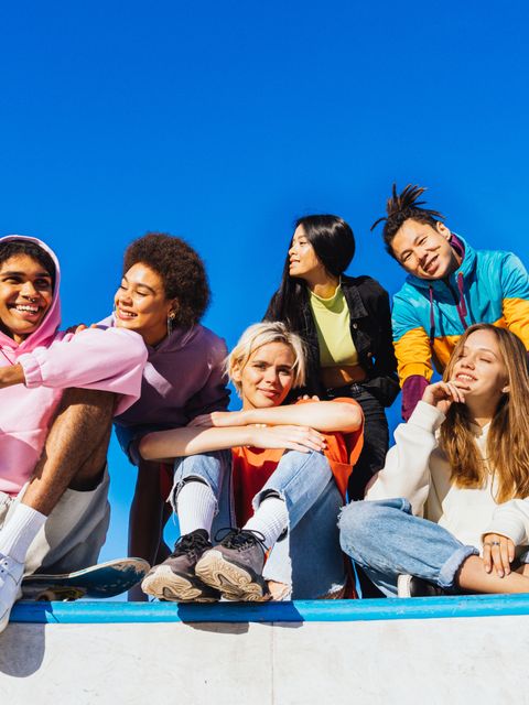 Eine Gruppe multikultureller Jugendlicher sitzt lachend draußen zusammen