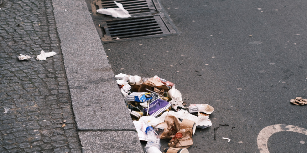 Am Straßenrand liegt achtlos weggeworfener Müll, eine Einwegverpackung und Servietten.