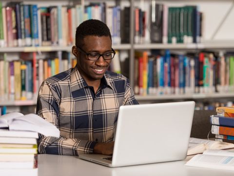 Student an seinem Laptop in der Bibliothek