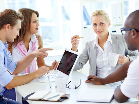 zwei Frauen, zwei Männer sitzen um einen Laptop und diskutieren