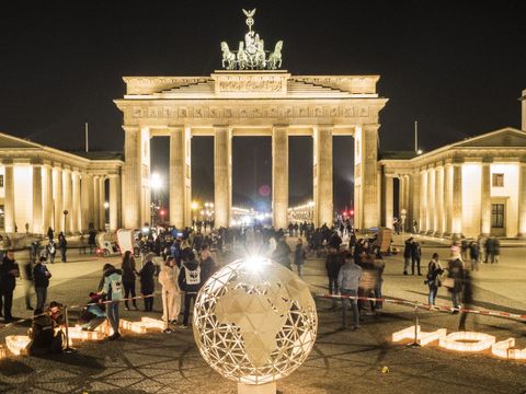 Brandenburger Tor in Berlin bei Nacht davor ein beleuchteter Globus aus Metall links das Wort Earth und rechts davon das Wort Hour