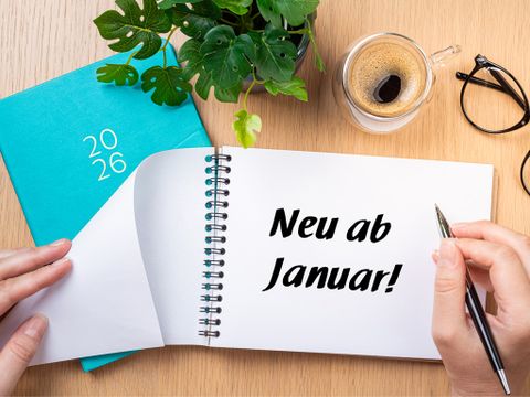 Ein weißer Block mit der Aufschrift "Neu ab Januar!" liegt auf einem Schreibtisch