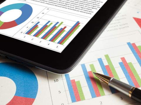 Statistische Aufbereitung auf Blatt mit Kugelschreiber und einem Tablet darüber liegend