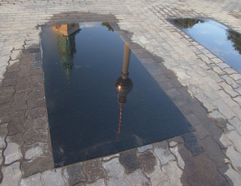 Reformations-Marienkirche und Fernsehturm spiegeln sich im regennassen Granit