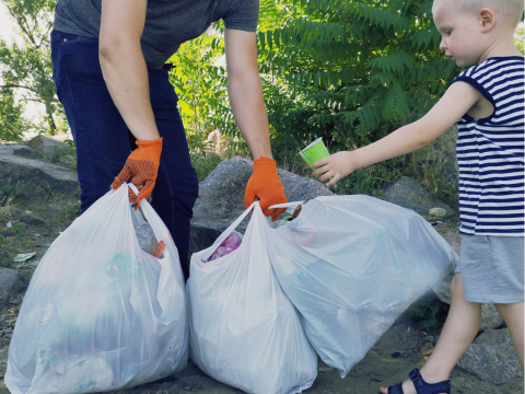 in einem Park wird gemeinsam mit einem Kind Müll aufgesammelt