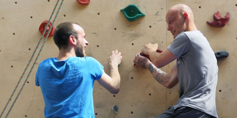Zwei junge Männer an der Kletterwand in einer Halle