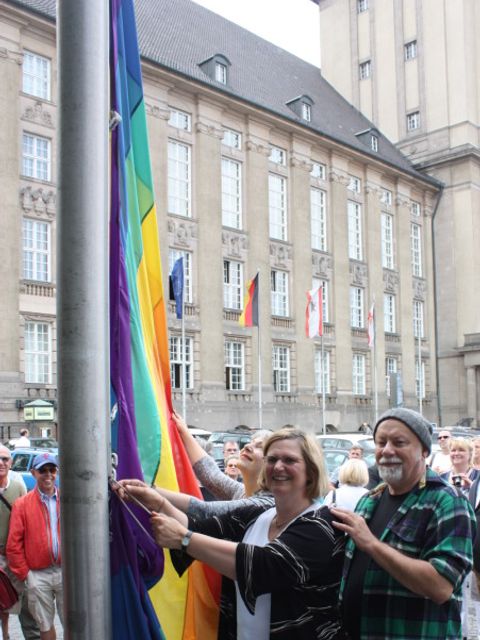 Bezirksbürgermeisterin Angelika Schöttler hisst gemeinsam mit dem Sprecher des Regenbogenfonds e.V., Gerhard Hoffmann, die Regenbogenfahne vor dem Rathaus Schöneberg (Bild: Pressestelle Tempelhof-Schöneberg)