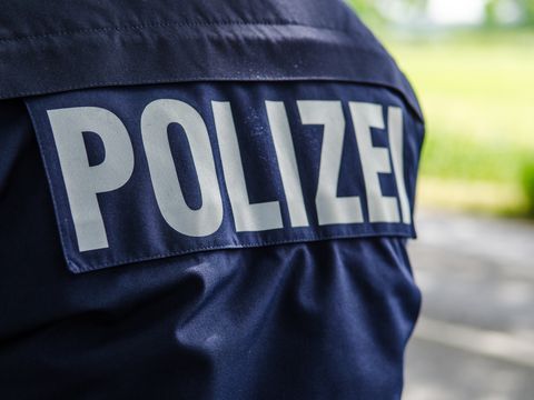 Rücken eines Polizisten mit der Aufschrift „Polizei“ auf der Jacke