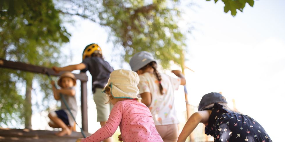 Kinder klettern Rampe an Holzspielplatz hoch