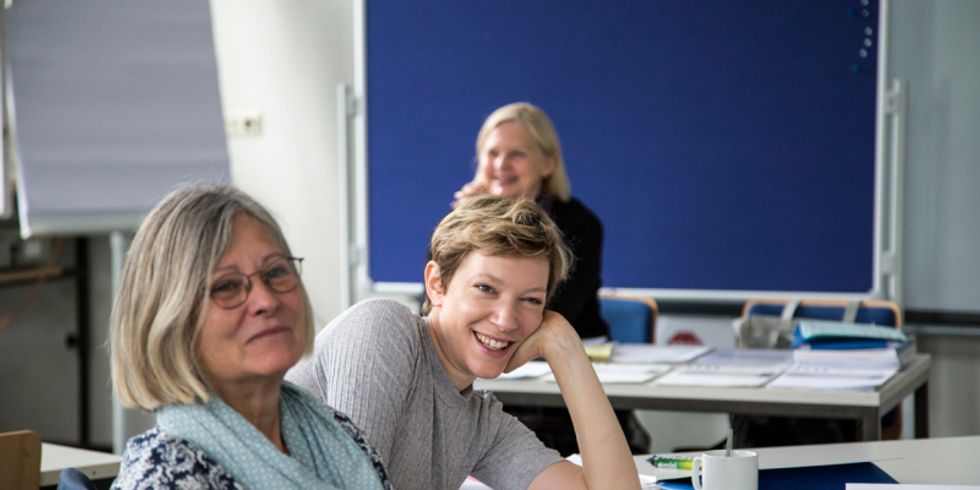 drei Frauen sitzen gemeinsam in einem Raum und lächeln