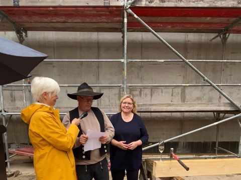 Hammer, Nagel und Glas sind vorbereitet, Zimmermann Sven Mollenhauer setzt zum traditionellen Richtspruch an. Im Bild, v.l.n.r. Martina Häusler, Leiterin der Serviceeinheit Facility Management, Sven Mollenhauer, Zimmerei Brummund, Bezirksstadträtin Dr. Carola Brückner (Bild: BA Spandau)