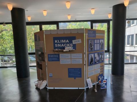 Ausstellungswand mit mehreren Postern, zu lesen ist die Überschrift Klimasnacks