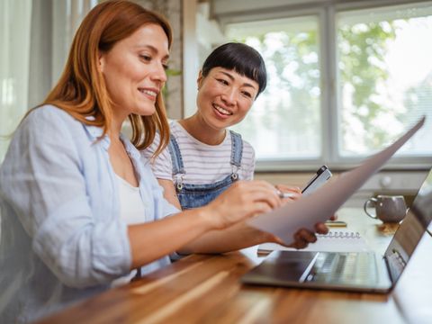 zwei Frauen sitzen an einem Tisch und beraten sich