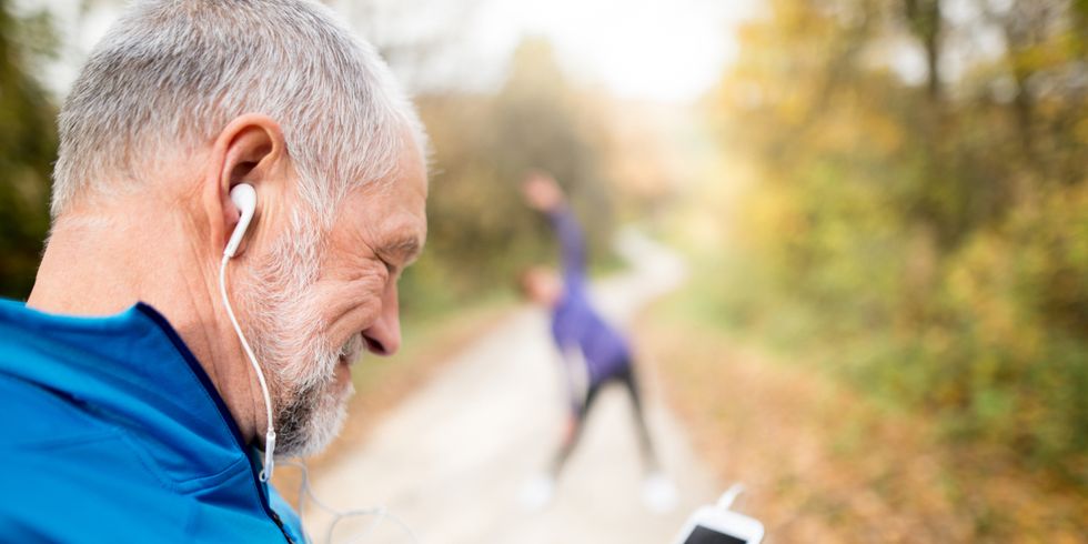 Senior runners in nature, stretching. Man with smartphone with e