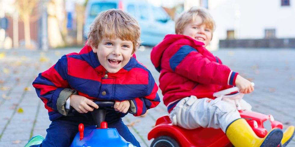 Two little kids boys playing with toy cars, outdoors