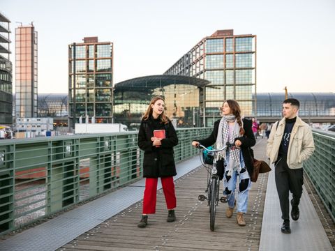 Gruppe von Studierenden laufen zusammen über eine Fußgängerbrücke über die Spree am Berliner Hauptbahnhof