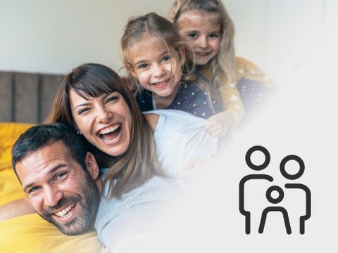 Vater, Mutter und zwei Kinder liegen lachend auseinander