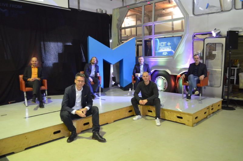 Fünf Männer sitzen auf einer Tribüne verteilt und schauen in die Kamera