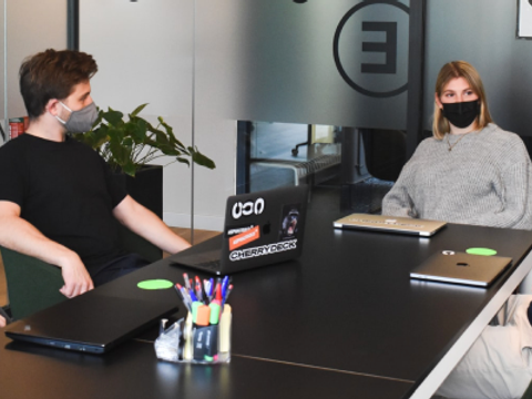 Beschäftigte sitzen mit medizinischer Maske zusammen in einem Meeting.