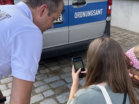 Ein Mitarbeiter des Ordnungsamts erklärt auf dem Blaulichtfest Mutter und Tochter digitale Angebote