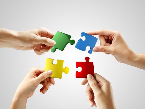 Hands and puzzle on gray background. Teamwork solving a puzzle