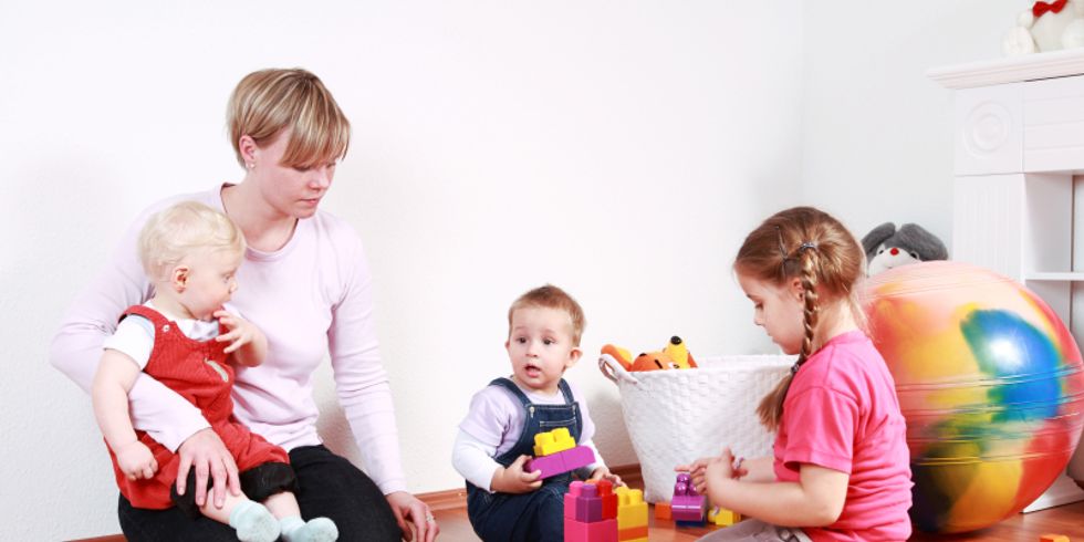 Kindergärtnerin und 3 Kinder spielen