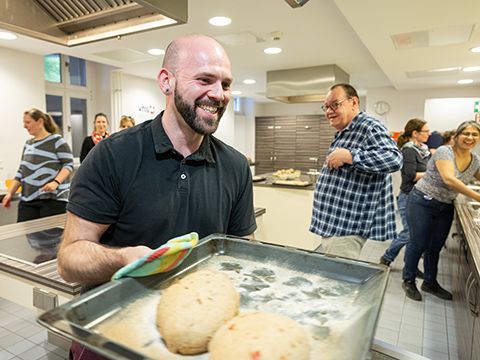 Ein Kursteilnehmer schiebt den Brotteig in den Ofen