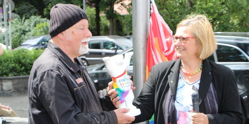 Bezirkbürgermeisterin Angelika Schöttler überreicht Gerhard Hoffmann einen BuddyBären zum 25. Jubiläum des Lesbisch-Schwulen Stadfestes. (Bild: Pressestelle Tempelhof-Schöneberg)