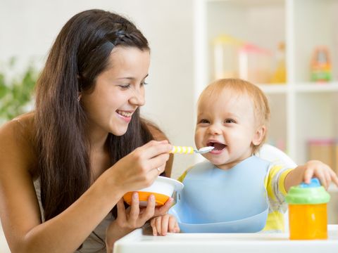 Kindertagespflegeperson füttert Kind mit einem Löffel