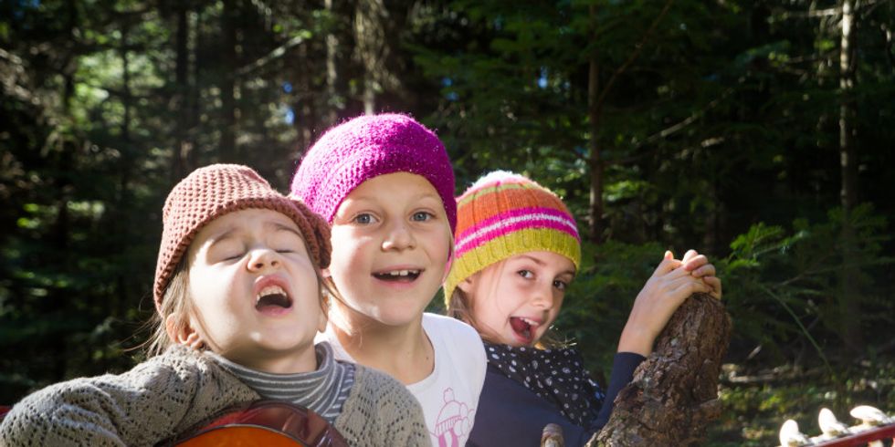 3 Mädchen sitzend und singend in einer Grünanlage