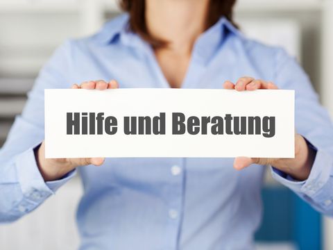 Eine Frau hält ein Schild mit der Aufschrift 'Hilfe und Beratung'