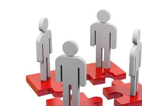 Vier Figuren stehen auf je einem Puzzleteil, welche zusammen passen