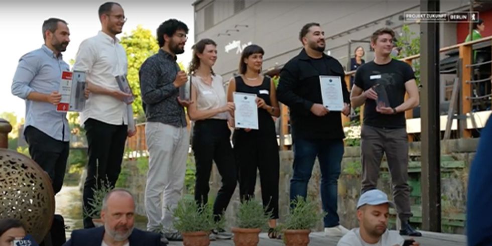 Gewinner:innen des DTA auf der Außen-Bühne mit Urkunden und Awards