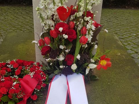 Blumengesteck vor der Gedenkstele an der Koppenstraße Ecke Singerstraße