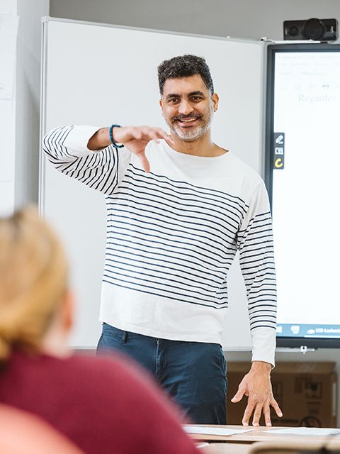 Kursleiter Yann-Nicolas Martial steht mit erhobener Hand vor einer Teilnehmerin. Er erklärt etwas und lächelt.