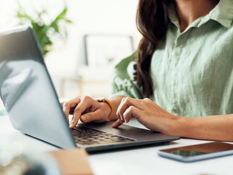 Hände einer Frau am Laptop; sie tippt am Schreibtisch