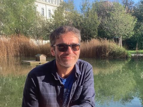 Kursleiter Floran Bayle mit Sonnenbrille in Frankreich mit Teich Schilf und Gutshaus im Hintergrund