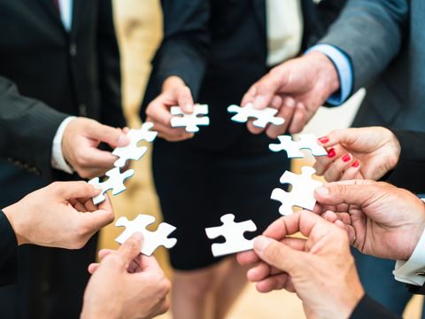 Mehrere Personen halten Puzzleteile zusammen