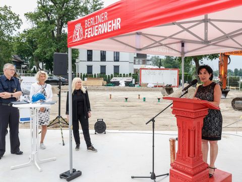 Extra zur feierlichen Grundsteinlegung ein feuerwehrrotes Rednerpult. Auf dem Bild von rechts: Bürgermeisterin Demirbüken-Wegner, Senatorin Spranger, BIM-Geschäftsführerin Möhring und Landesbranddirektor Dr. Homrighausen. (Bild: BIM / Jochen Eckel)