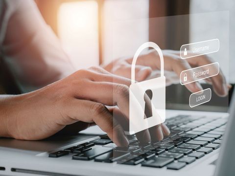 Frauenhand tippt auf einer Tastatur, während auf dem Bildschirm Login und Passwort angezeigt werden
