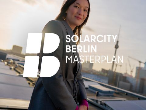 Frau auf Dach, lächelt in Kamera. Hinter ihr eine Photovoltaianlage und ein Ausblick über Berlin.