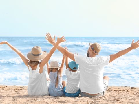 Rückansicht zweier Erwachsener und zweier Kinder am Strand