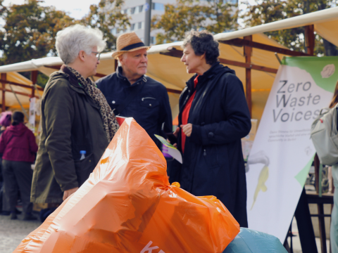 Menschen im Gespräch auf dem Müllfest 2025. Im Vordergrund sind Müllsäcke zu sehen