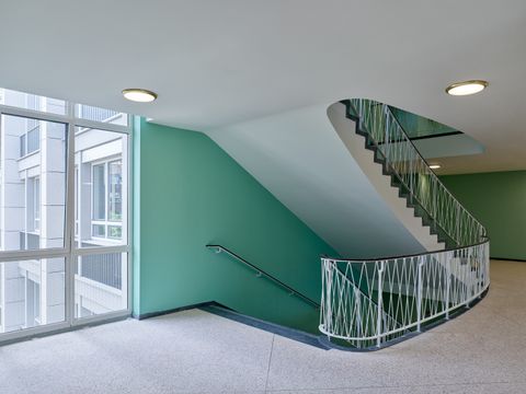 Blick auf das Treppenhaus im 4. OG nach der Sanierung mit den bauzeitlichen Deckenleuchten, Juni 2024