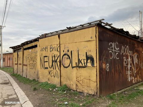 Foto von heruntergekommenen Holzbaracken mit dem Schriftzug Neukölln