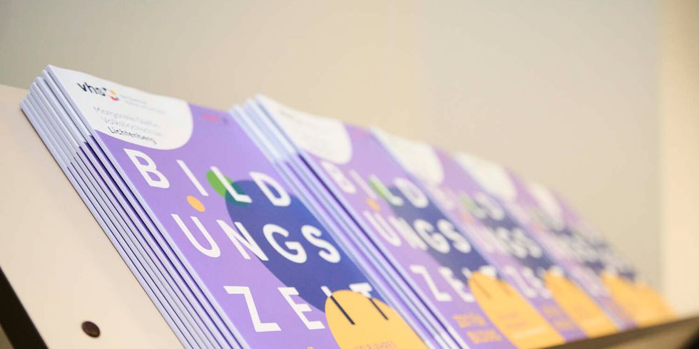 Auslage mit Programmheften der VHS Lichtenberg. Auf der Titelseite steht "Bildungszeit. Zeit für Bildung".