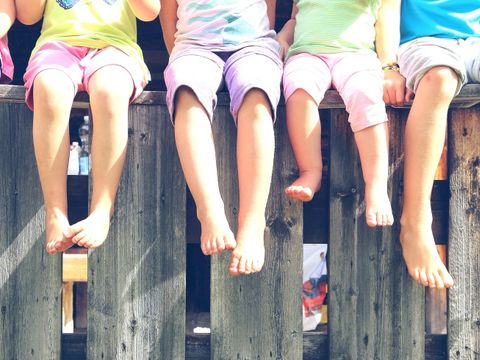 Kinderbeine bäumeln über einem Zaun
